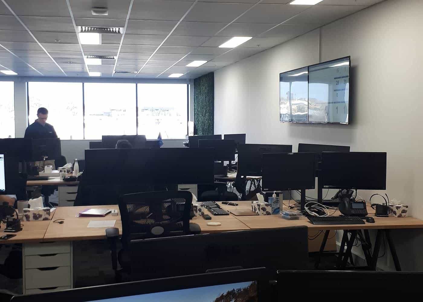 Rows of office desks with monitors in an open-plan office