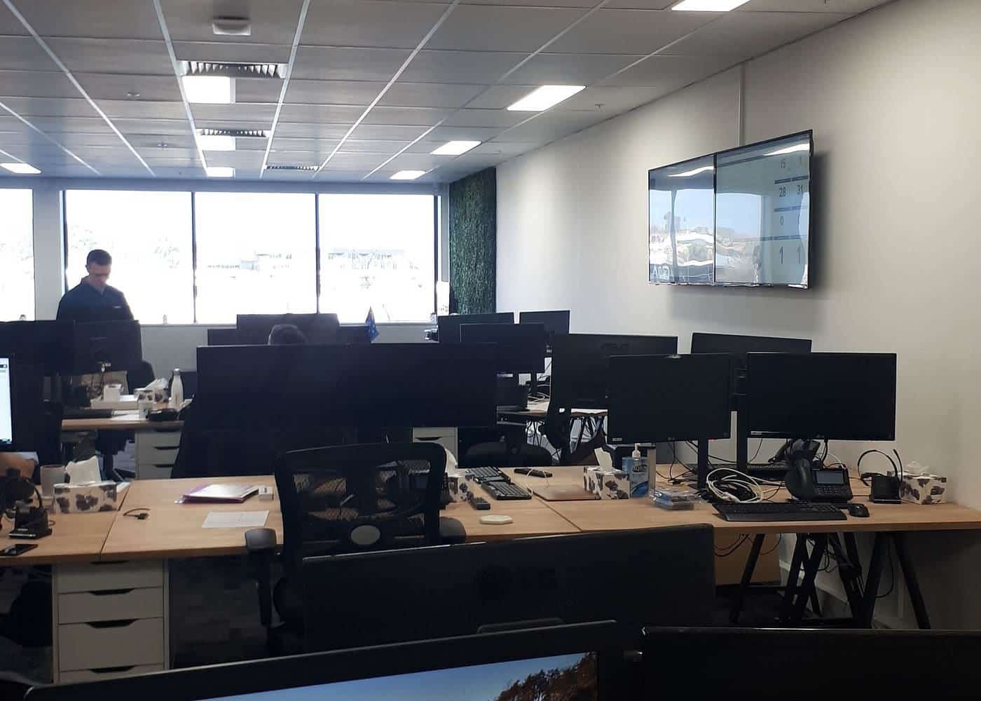 Rows of office desks with monitors in an open-plan office