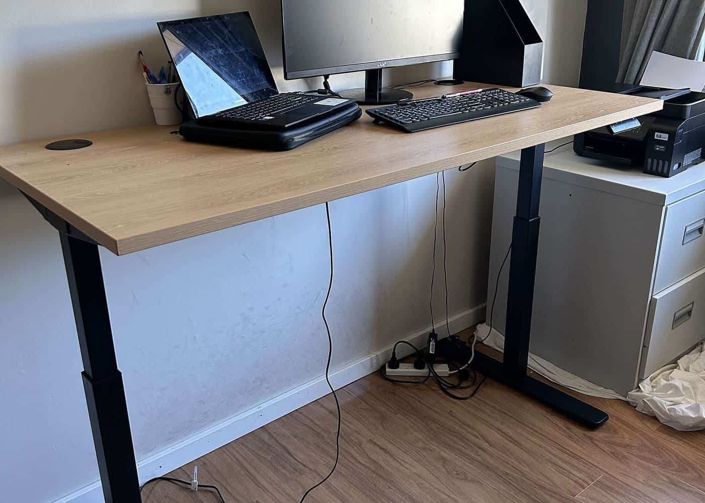 A height-adjustable desk with a laptop and monitor in an office