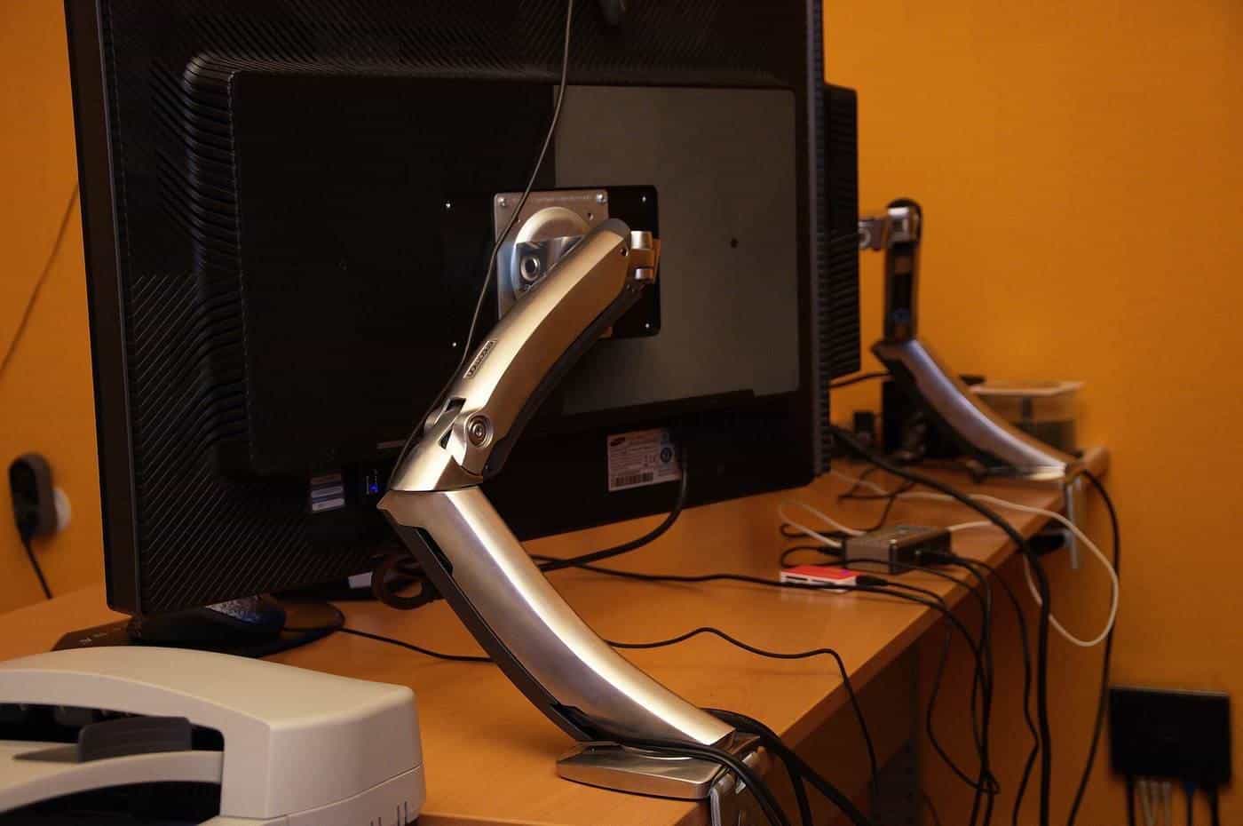 Monitors mounted on adjustable monitor arms above a desk
