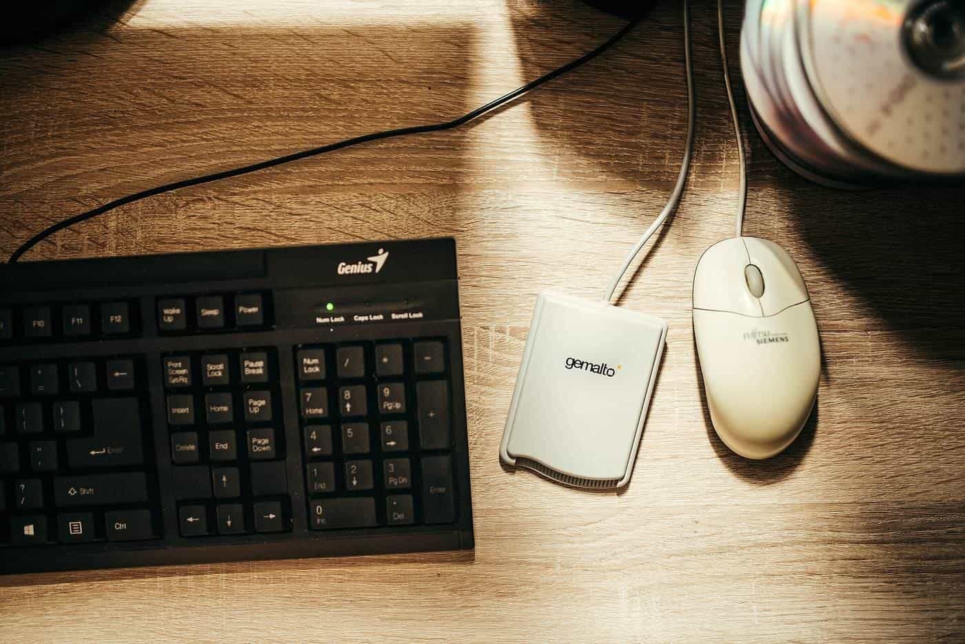 A keyboard and mouse on a wooden desk