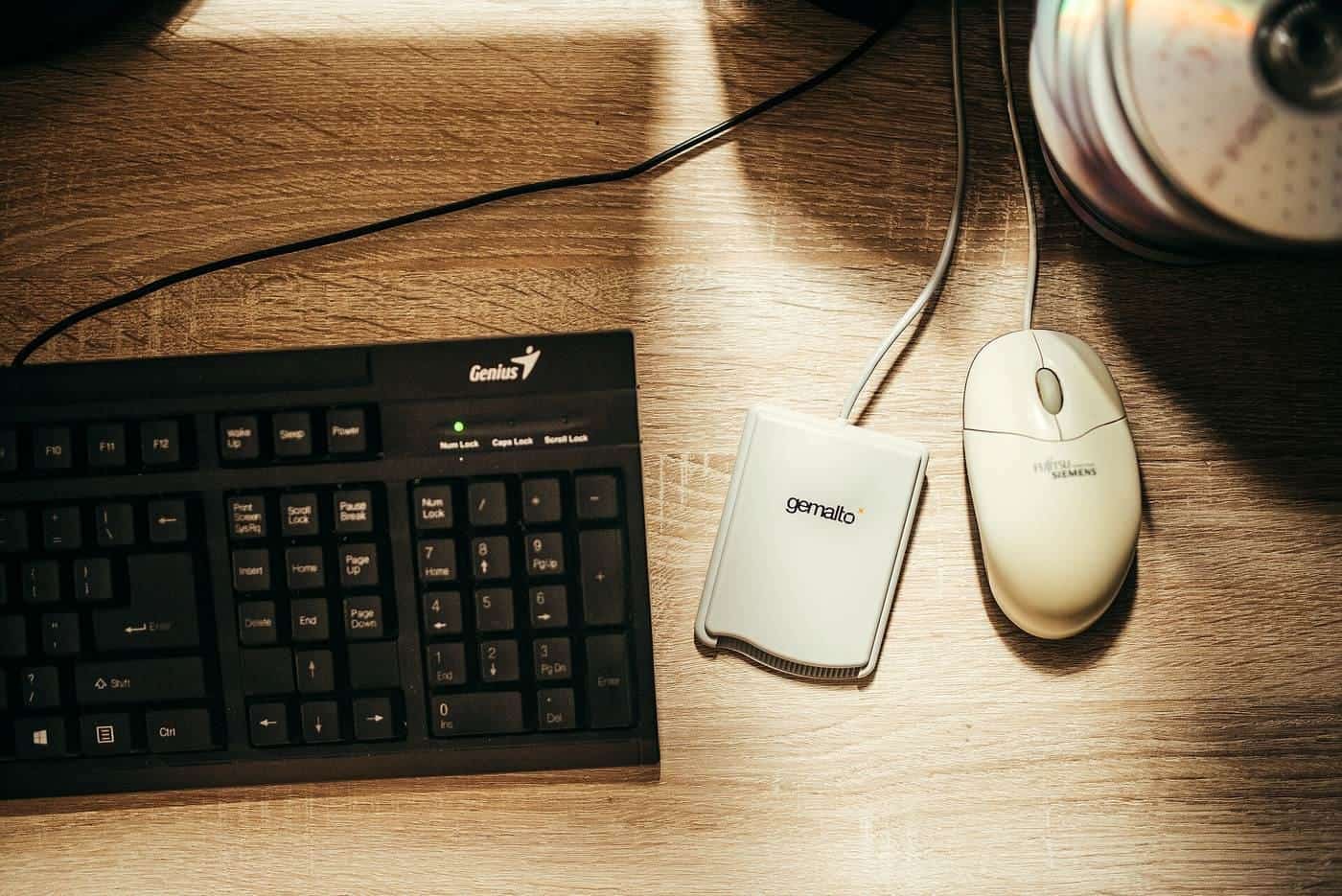 A keyboard and mouse on a wooden desk
